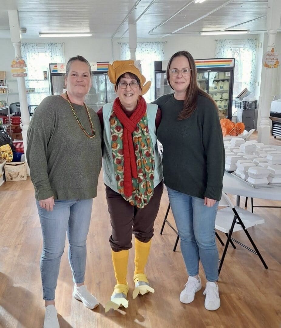 Three smiling women, center in yellow duck costume