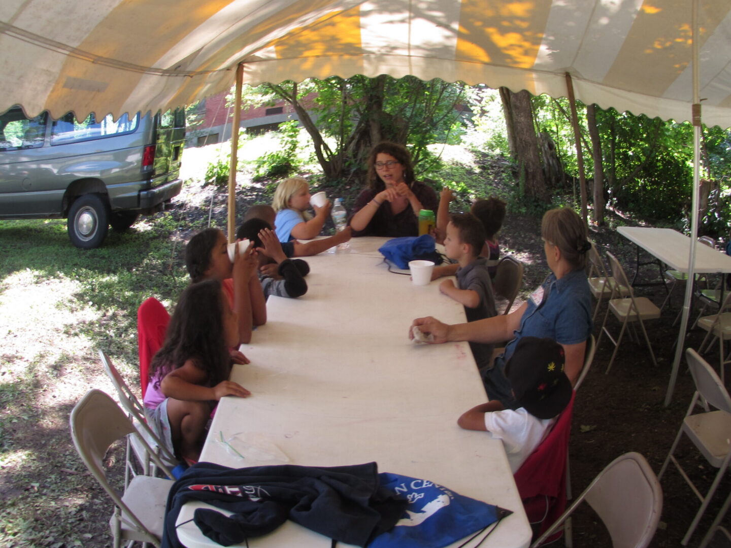 Children enjoying drinks under a tent.